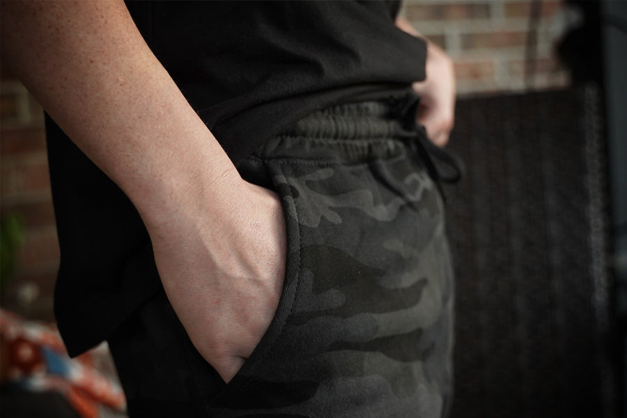 Person wearing black pants with camouflage pattern in a casual setting.