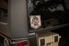 Duck camo decal on a vehicle window with 'Stay the Course' text, next to a YETI cooler.
