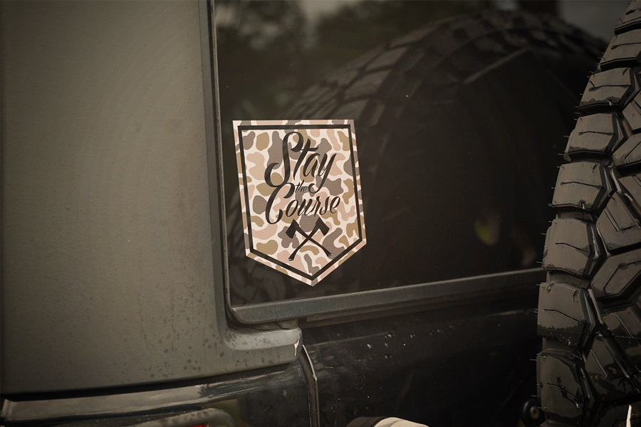 Duck Camouflage-style decal on a vehicle with 'Stay the Course' text, next to a tire.