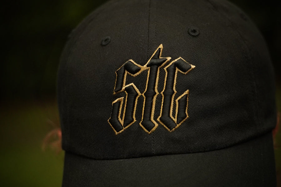 Black cap with gold logo on a blurred background
