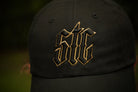 Black cap with gold logo on a blurred background