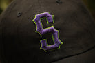Black cap with purple and green embroidered logo on a blurred background