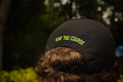 Black cap with 'Stay the Course' text worn by a person outdoors