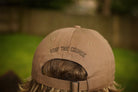 Brown cap with 'Stay the Course' text on a blurred outdoor background
