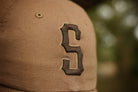 Brown cap with a logo on a blurred natural background