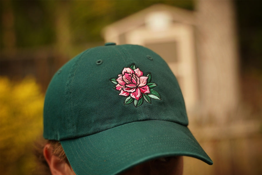 Green cap with a pink azalea embroidery on a blurred background
