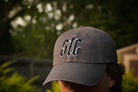 Gray cap with 'STC' logo worn by a person outdoors