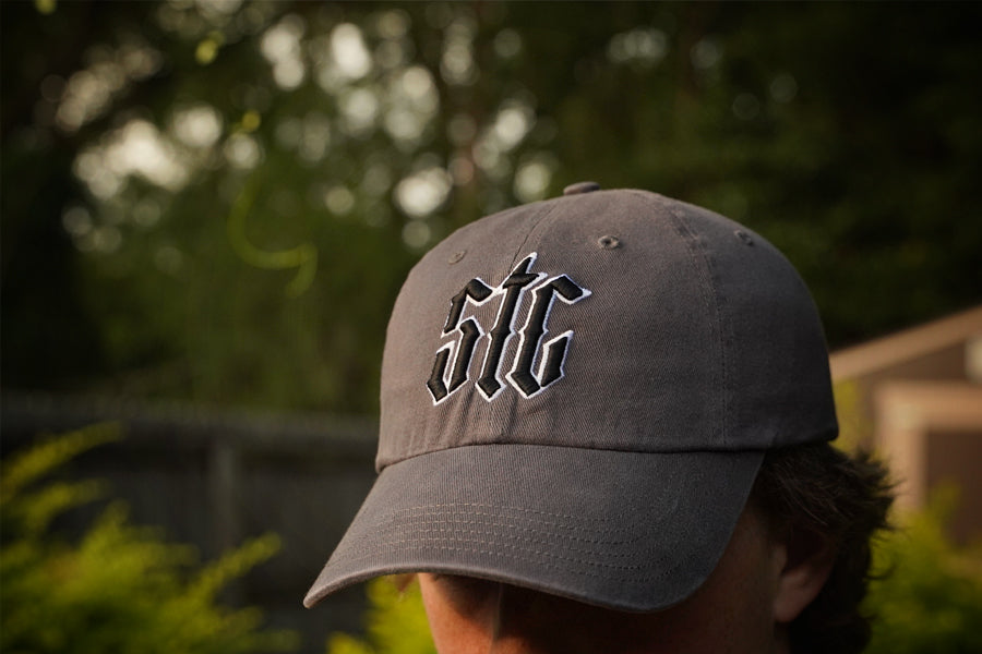 Gray cap with 'STC' logo worn by a person outdoors
