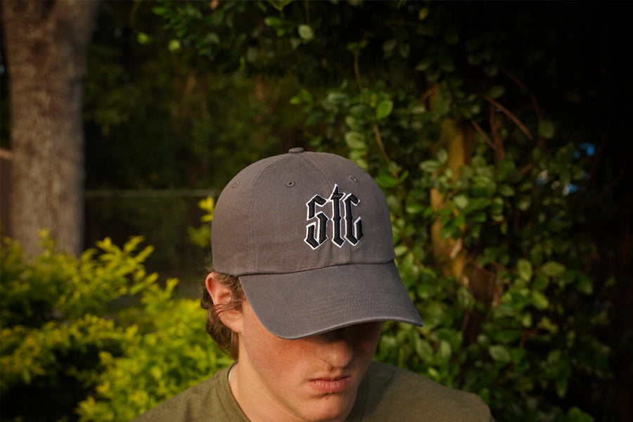 Person wearing a gray cap with STC  logo outdoors