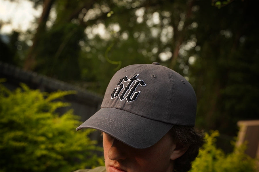 Person wearing a gray cap with STC logo outdoors