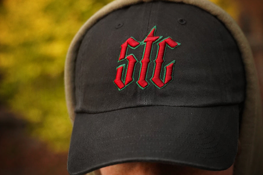 Black cap with red and green logo worn by a person, blurred background