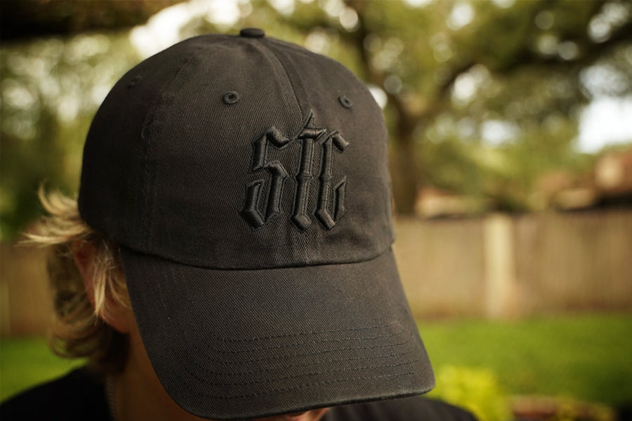 Black cap with STC  logo worn by a person outdoors