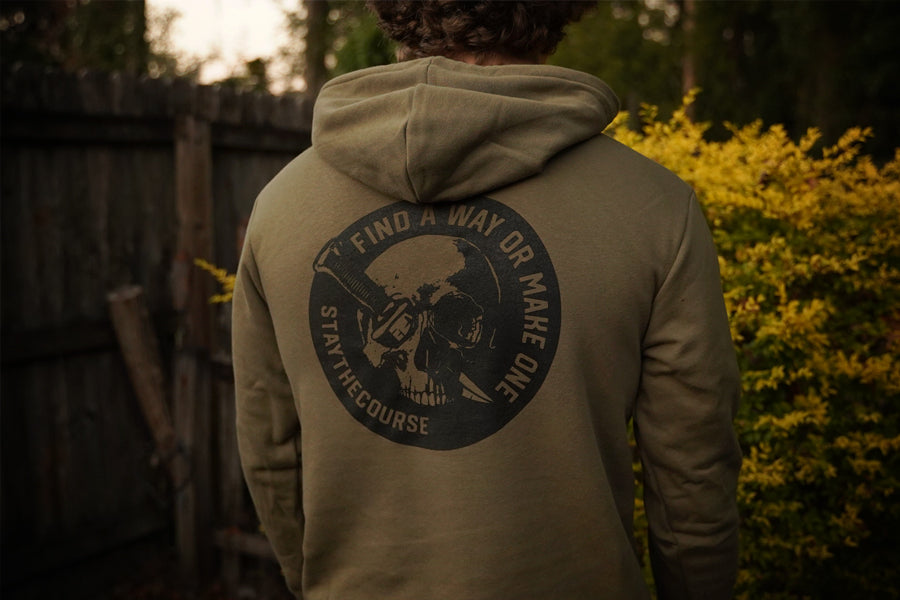 Person wearing a green hoodie with a graphic design on the back, standing outdoors.