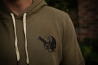 Green hoodie with a black skull design on the chest, blurred background