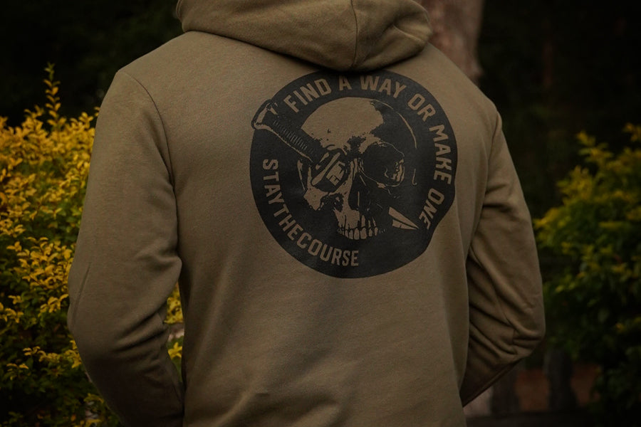 Person wearing a hoodie with a skull design and text on the back, standing outdoors.