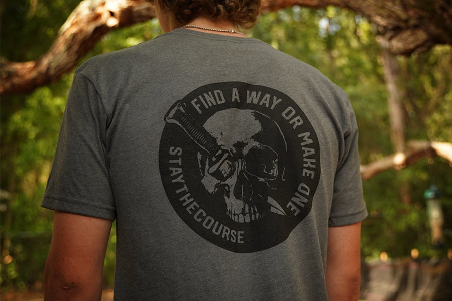 Person wearing a gray shirt with black graphic print that says "Find a way or make one - Stay the Course"