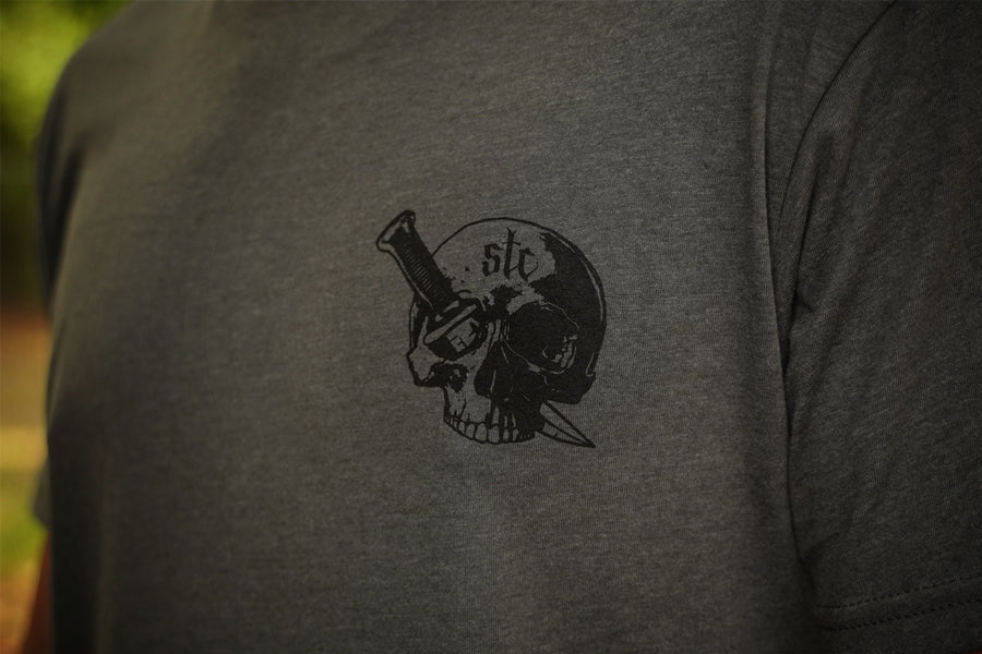 Person wearing a gray shirt with black graphic of a skull and dagger