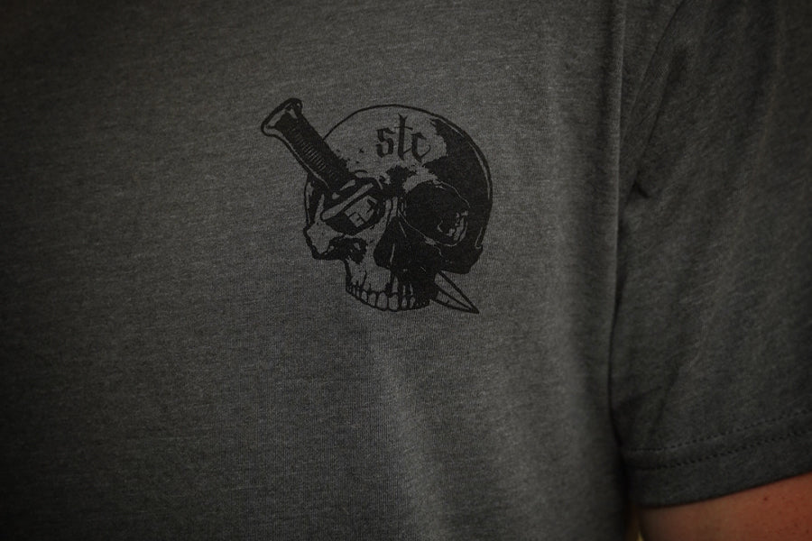 Person wearing a gray shirt with black graphic of a skull and dagger