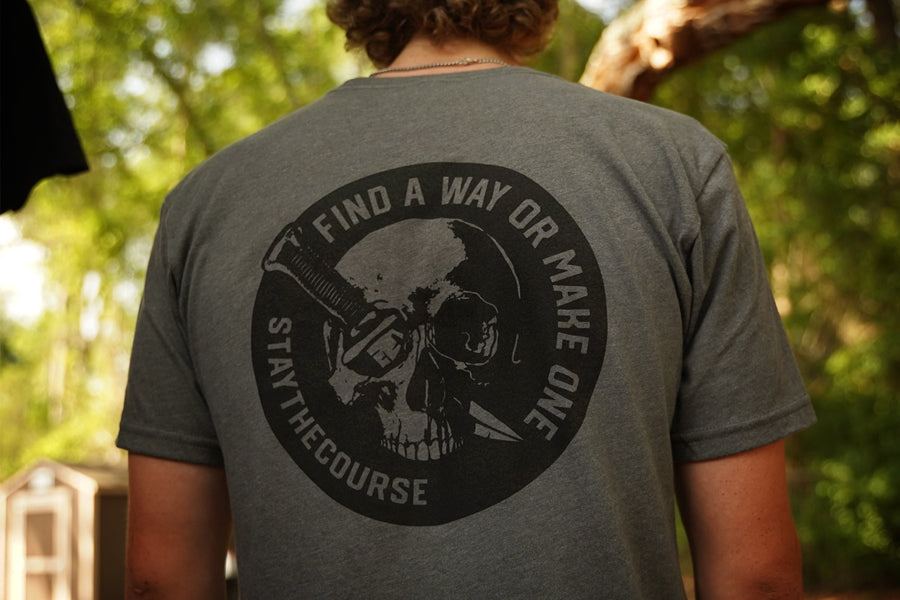 Person wearing a gray shirt with black graphic print that says "Find a way or make one - Stay the Course"
