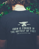 Person wearing a black t-shirt with a motivational quote and an anvil graphic.