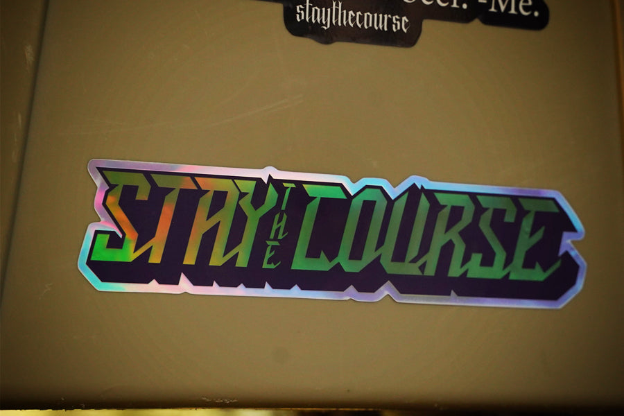 Holographic 'Stay the Course' sticker on a beige surface