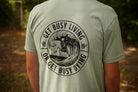 Person wearing a green shirt with black graphic that says "get busy living or get busy dying"