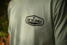 Person wearing a green shirt with black graphic that says "Stay the Course"