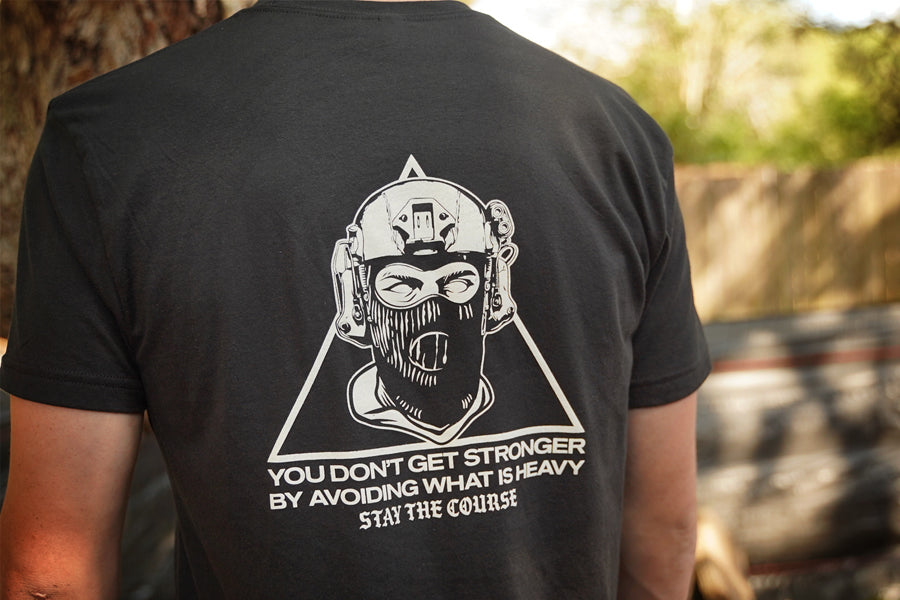 Person wearing a black t-shirt with a graphic design on the back, featuring text and a stylized figure.