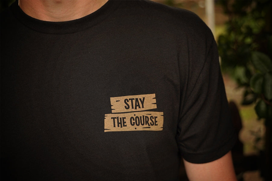 Black t-shirt with 'Stay The Course' text on a blurred background