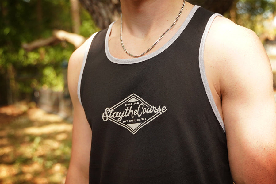 Person wearing a black tank top with 'Stay the Course' logo outdoors.