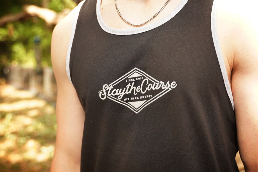 Person wearing a black tank top with 'Stay the Course' logo outdoors.