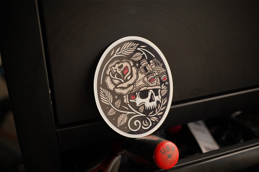Decorative sticker with skull and rose design on a black surface