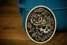 Decorative sticker with skull and rose design on a blue container