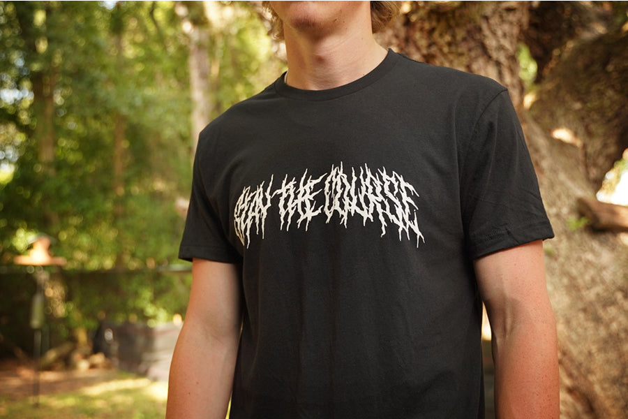 Person wearing a black T-shirt with "Stay the Course" printed in white in heavy metal style