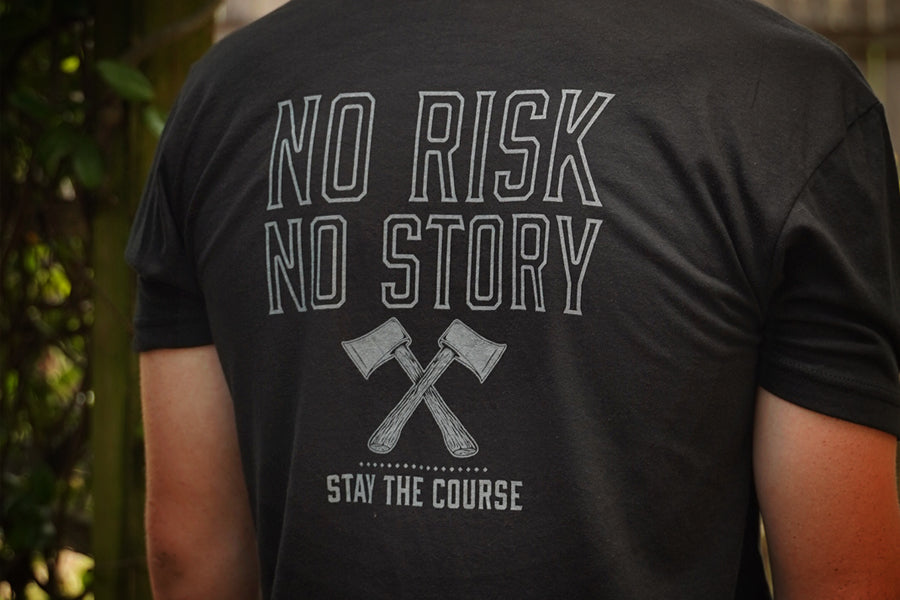 Person wearing a black t-shirt with 'No Risk No Story, Stay the Course' text and graphic on the back.