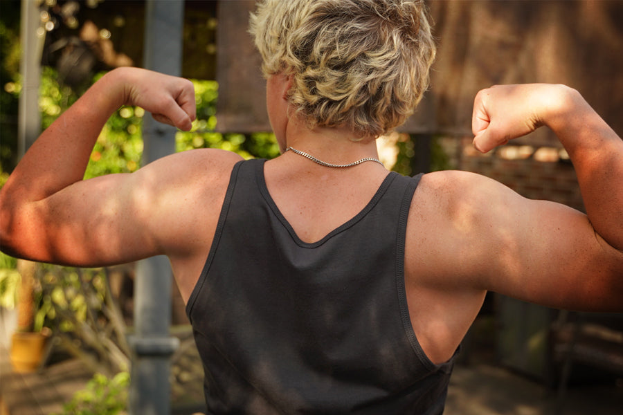 Person flexing muscles outdoors with a garden background