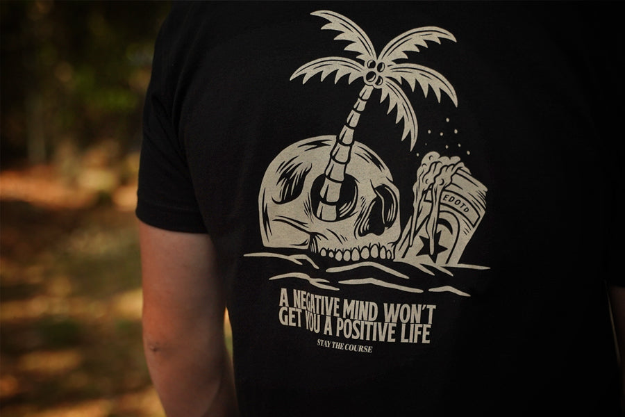 Black t-shirt with a white skull and palm tree design and motivational quote.