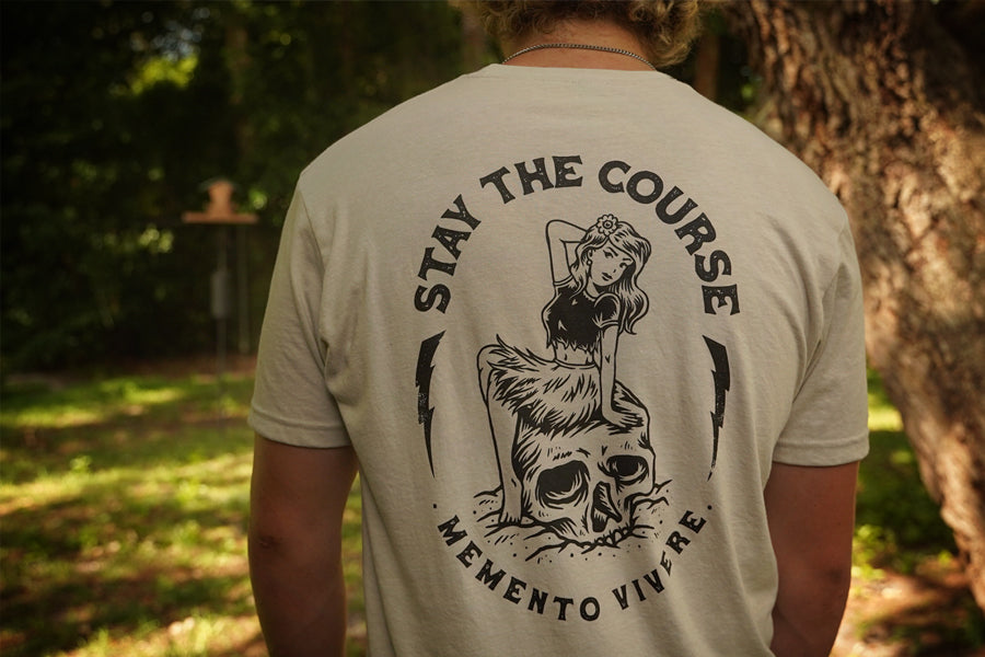 Person wearing a t-shirt with 'Stay the Course' design outdoors