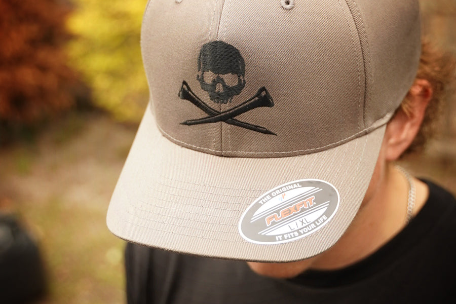 Gray cap with skull and golf tees design worn by a person outdoors