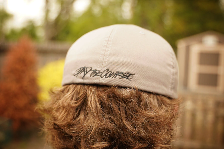 Person wearing a cap with 'By the Course' branding outdoors
