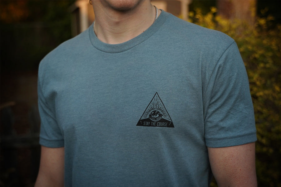 Person wearing a blue t-shirt with a triangle logo on a blurred background