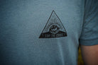 Blue t-shirt with a black triangle logo featuring an eye and 'Stay the Course' text.
