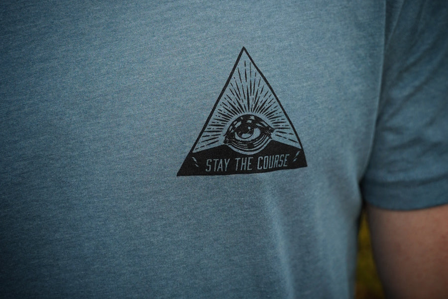 Blue t-shirt with a black triangle logo featuring an eye and 'Stay the Course' text.