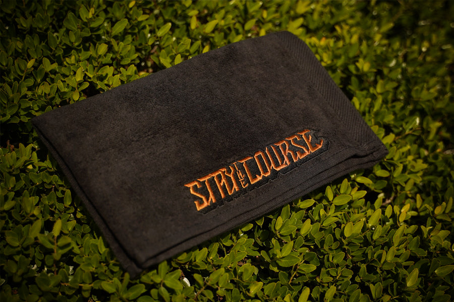 Black towel with 'Stay the Course' text on grass