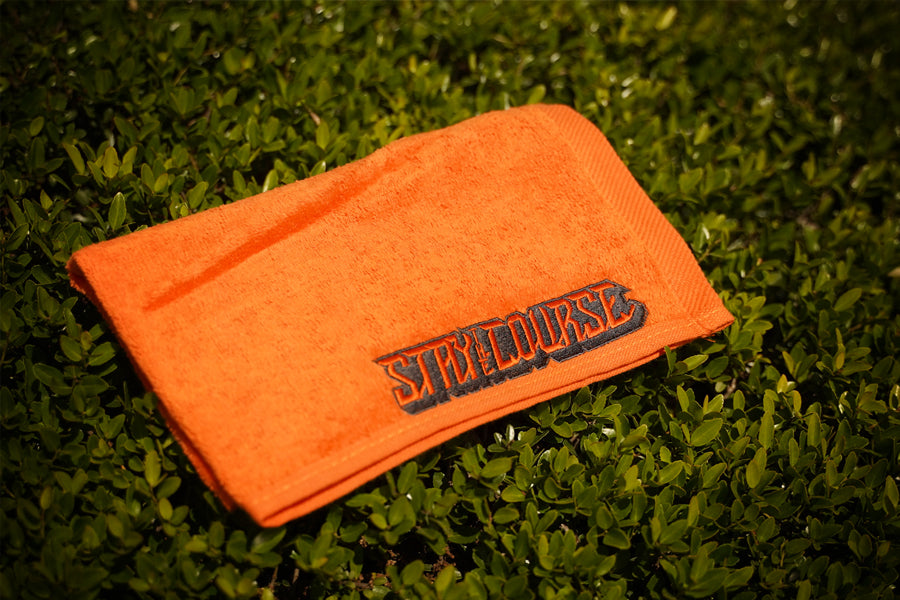 Orange towel with 'Stay the Course' logo on grass