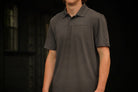 Person wearing a dark gray polo shirt with brand logos on a black background