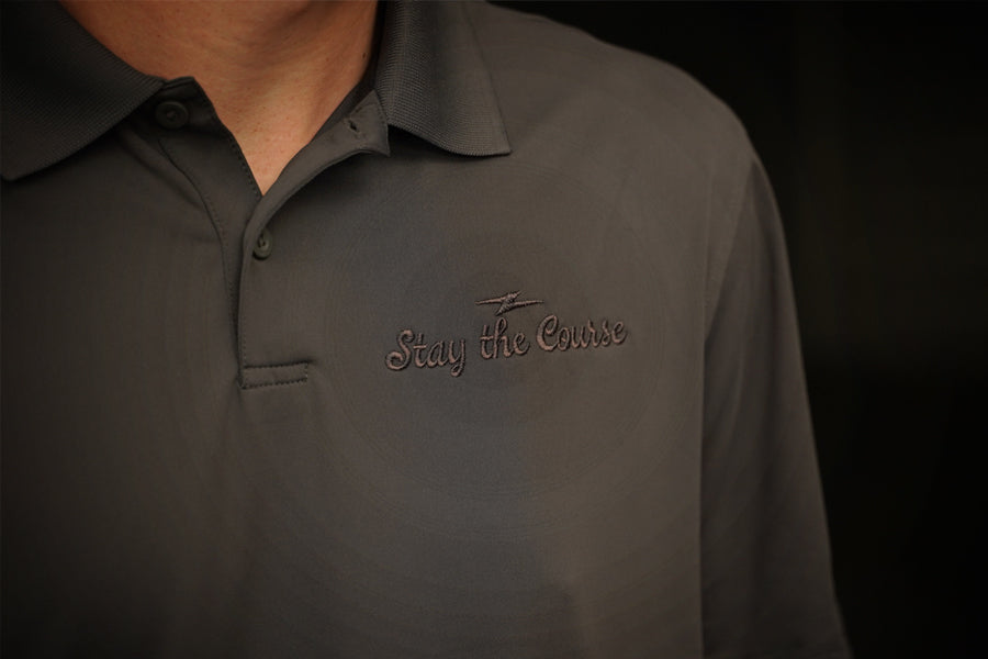 Dark gray polo shirt with 'Stay the Course' logo on a black background