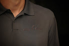 Dark gray polo shirt with 'Stay the Course' embroidery on a black background