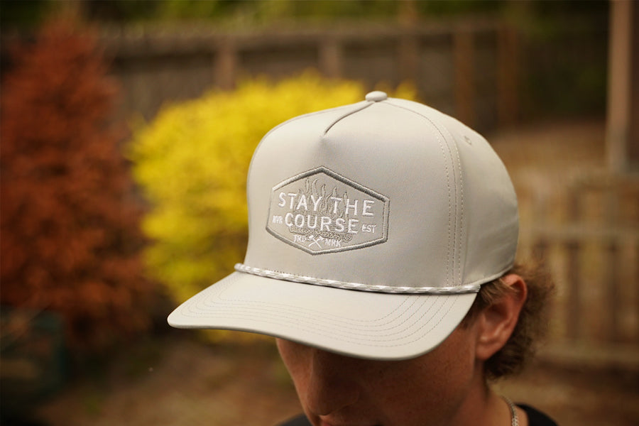 Person wearing a gray cap with 'Stay the Course' logo outdoors