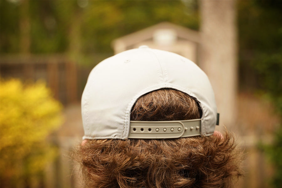 Person wearing a gray cap with a blurred outdoor background